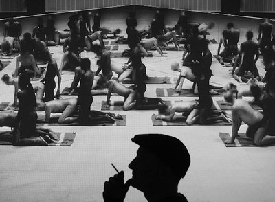 El artista Santiago Sierra, fotografiado en penumbra, con su obra  Los penetrados  de fondo.