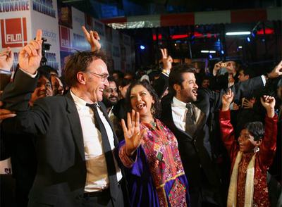 Danny Boyle, a la izquierda, codirector de  Slumdog millionaire,  baila el jueves en la alfombra roja con los actores Shabana Azmi y Anil Kapoor.
