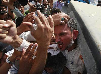 Un activista protesta en Karachi rodeado de policías de paisano.