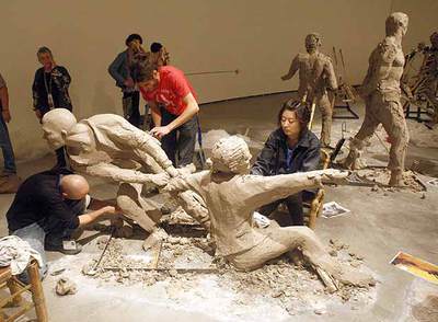 Dos estudiantes de Bellas Artes modelan una figura de la instalación  Patio de la recaudación de la renta,  junto a una artista china.