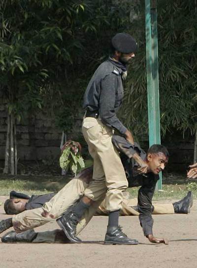 Agentes paquistaníes asisten a un compañero herido en el ataque a la academia de policía de Lahore por unos terroristas.