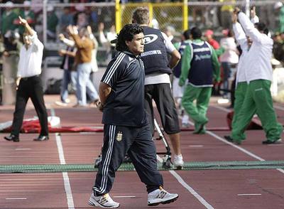 Diego Armando Maradona vuelve a su banquillo mientras los bolivianos celebran uno de sus goles.