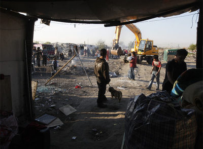Un grupo de chabolistas de El Cañaveral recoge sus cosas mientras las máquinas, al fondo, van tirando otras infraviviendas.