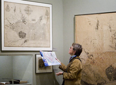 Una visitante de la exposición  Il-luminacions  en el CCCB compara el plan de Cerdà de 1859 con un plano actual de Barcelona.