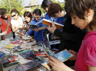 Varias personas ojean libros en un intercambio solidario en la Puerta de Toledo.