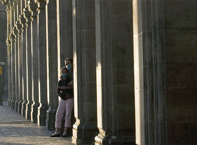 Dos jóvenes con mascarillas en una calle solitaria de Ciudad de México.
