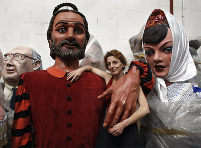 Ana Cecilia Tejada, la restauradora de los gigantes y cabezudos,  abrazada  por san Isidro en el hangar donde se guarda.