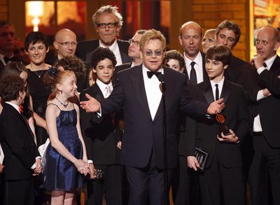 Elton John agradece los premios, rodeado de los intérpretes de la obra.