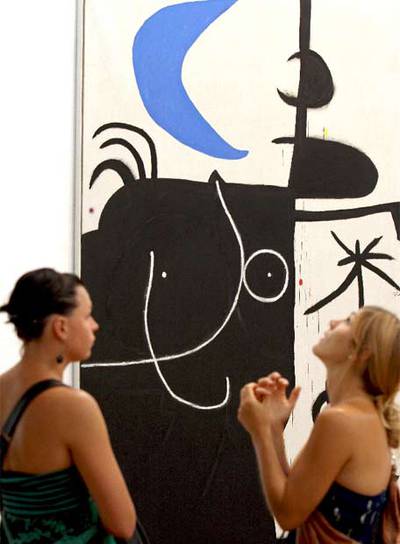 Dos visitantes ante  Mujer delante de la luna II  (1974), una de las obras de la exposición.