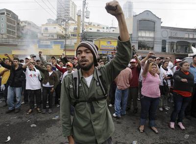 Partidarios del depuesto presidente Manuel Zelaya entonan el himno nacional frente a la residencia de éste en Tegucigalpa.rnRoberto Micheletti.