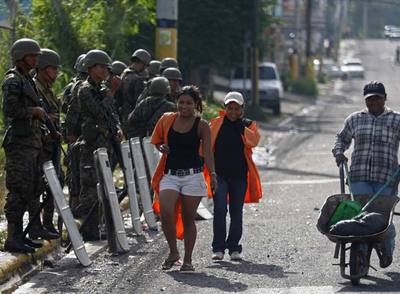 Tres trabajadores superan un control militar situado cerca de la residencia presidencial en Tegucigalpa.
