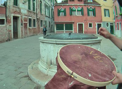 Una  performer  borda narcomensajes con hilo de oro sobre tela ensangrentada en Venecia.