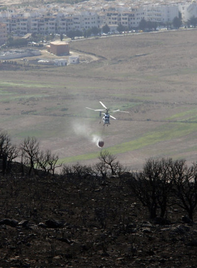 Un helicóptero arroja agua en la zona del incendio.