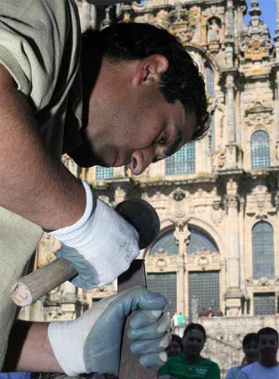 Un participante del concurso de canteiros esculpe su adoquín enfrente de la Catedral de Santiago.