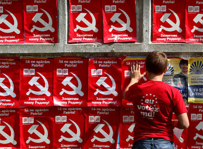 Un moldavo pega carteles del Partido Comunista en los que se lee 