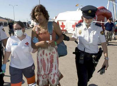 Una voluntaria de la Cruz Roja y una policía conducen a una  sin papeles  que llegó el viernes a Dénia.