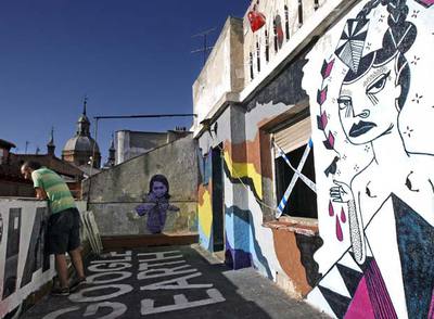 La terraza del quinto piso del Patio Maravillas, con los tejados de Malasaña de fondo, sirve de escenario para las obras temporales del taller de arte urbano.rnArriba, las escaleras decoradas con los restos de una exposición. A la derecha, la entrada.