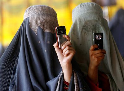 Dos mujeres ataviadas con el  burka  hacen fotos con sus móviles durante un mitin de Hamid Karzai en Kandahar.rnMujeres afganas se disponen a votar el 20 de agosto pasado.