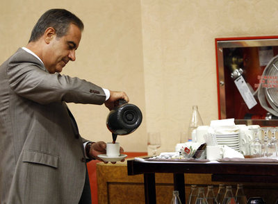 Celestino Corbacho se sirve un café antes de comenzar su comparecencia parlamentaria.