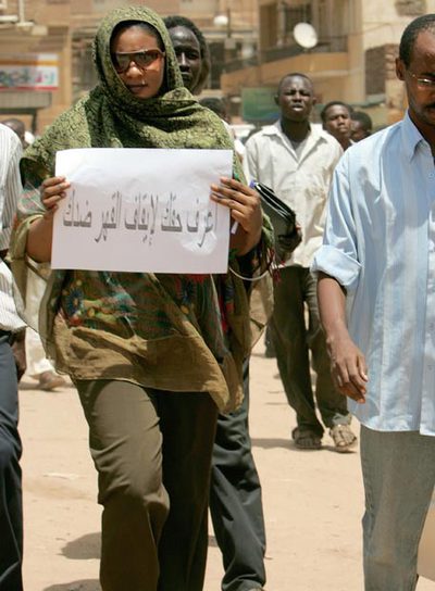 Husein, con pantalones, a la salida del juicio, con un cartel que dice: 