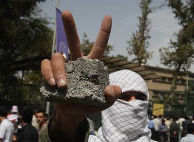 Un estudiante iraní hace el signo de la victoria con una piedra en la mano durante la manifestación de solidaridad con el pueblo palestino.