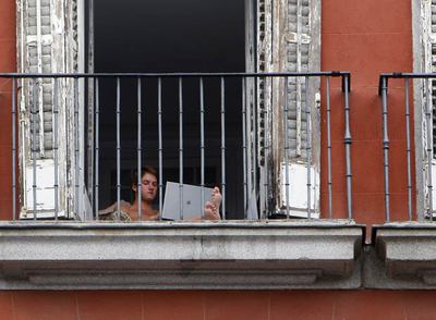 Un joven utiliza un ordenador personal en el balcón de un domicilio que da a la plaza Mayor.