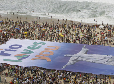Una gran pancarta, con el lema  Río te ama,  en la playa de Copacabana.