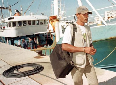 Uno de los detenidos camina esposado delante del barco   Regina Maris,   propiedad del   narco   Laureano Oubiña y decomisado en octubre de 1999 con 12,5 toneladas de hachís.