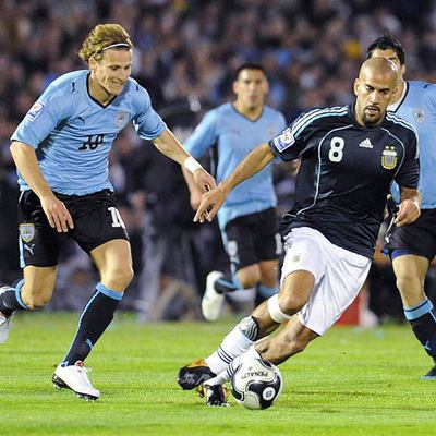 Forlán persigue a Verón durante el partido de ayer en Montevideo.