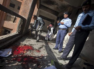 Especialistas en explosivos inspeccionan el lugar del atentado perpetrado ayer en la Universidad Islámica de Islamabad.