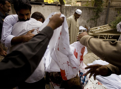 Dos hombres se abrazan en el lugar del atentado junto a varios cadáveres cubiertos con sábanas.