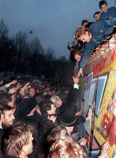 El canciller alemán Helmut Kohl estrecha la mano de un ciudadano berlinés  encaramado en lo alto del Muro de Berlín, cerca de la Puerta de Brandenburgo, el 22 de diciembre de 1989.rnFoto: EFE