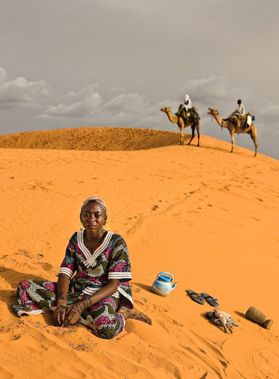 MariamarnTiene 14 años y se llama Mariama Sanda. Para ayudar a su familia, va a trabajar a la casa de otra familia más pudiente diez horas diarias. Cobra diez euros al mes. Comenzó a realizar trabajos domésticos con sólo 11 años. La retratamos en la Gran Duna, cerca de Niamey. Se ha vestido para la ocasión con su traje y pendientes favoritos, más los tatuajes de henna. Posa con sus objetos más queridos: una muñeca de plástico con palos en brazos y piernas, una tetera para las abluciones