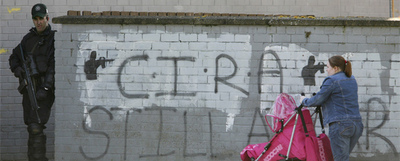 Una mujer empuja el carro de su bebé ante un miembro de la policía de Irlanda del Norte.