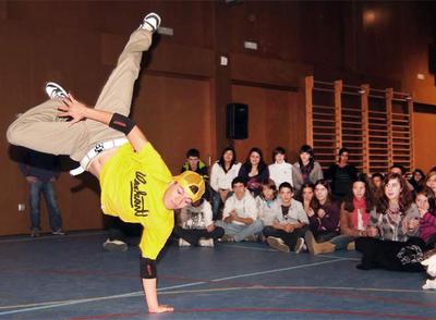 Uno de los  b-boys  practica el baile denominado  breakdance  ante la expectación de alumnos de los institutos de Ferrol.