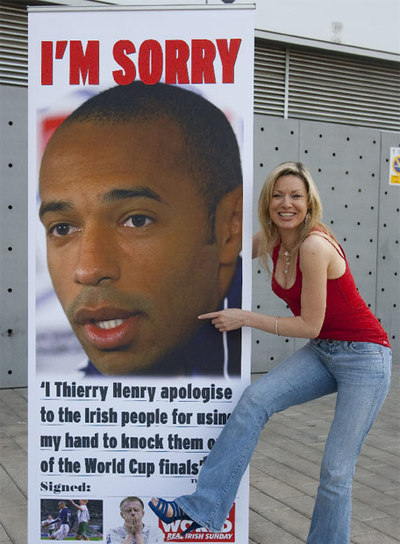 Una periodista, con un cartel de Henry en la ciudad deportiva del Barça.