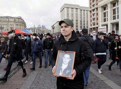 Un miembro de una organización antifascista sostiene una fotografía del líder del movimiento, Iván Jutorskói, durante un acto en su memoria.