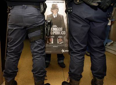 Un trabajador del hospital Clínico recibe a Aguirre con una pancarta crítica.