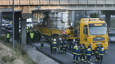 Un grupo de bomberos observa el camión articulado que transportaba un transformador, tras quedar encajado en un puente de la M-40.