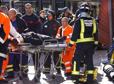 Un hombre herido por el desprendimiento de un tejado metálico en la calle de la Paz de Valencia es trasladado a una ambulancia.rnUn coche aplastado por un árbol derribado por el viento en la calle del Rey Saúd de Valencia.