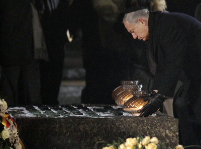 El primer ministro israelí, Benjamín Netanyahu, deposita una vela a los pies de un monumento en el campo de Auschwitz.
