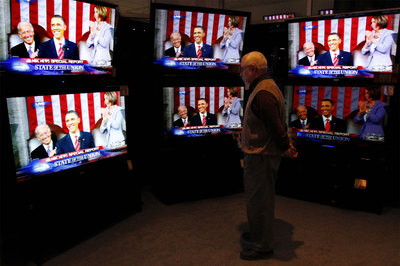 El dueño de una tienda de electrodomésticos de Glenview (Illinois) sigue por televisión el discurso.