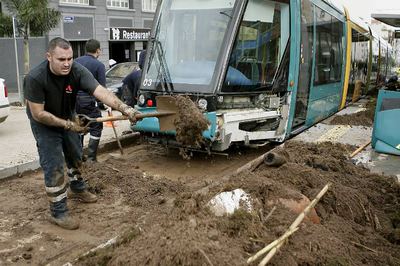 Varios bomberos retiran lodo y restos acumulados por la lluvia en las vías del tranvía de Santa Cruz de Tenerife.