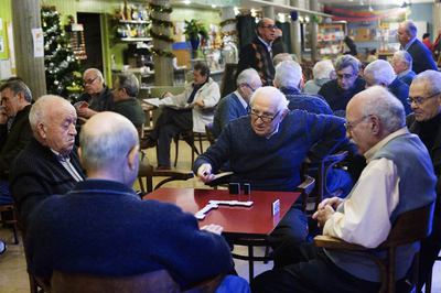 Grupos de ancianos jugando al dominó y a las cartas en el casal Gran Joan Casanelles de Barcelona.