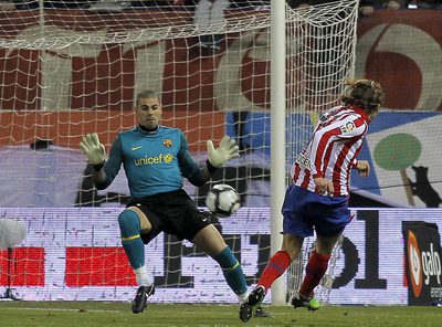 Forlán, en el momento de cruzar el balón lejos del alcance de Víctor Valdés para lograr el primer gol del Atlético ante el Barcelona.