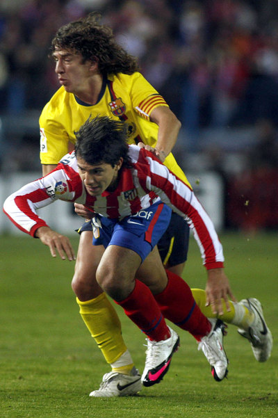 Puyol y Agüero pugnan por el balón.