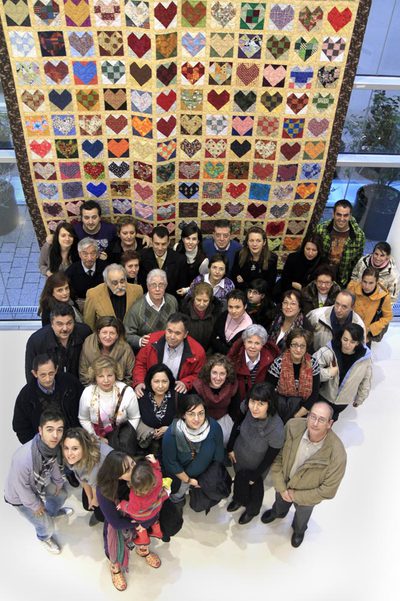 Miembros de la Asociación 11-M, delante del  patchwork   Trazos y puntadas para el recuerdo. 