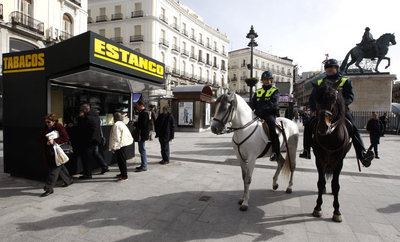 Dos policías municipales a caballo pasan por delante de los nuevos quioscos instalados en la Puerta del Sol.