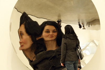 Una mujer se refleja en la obra   Poniendo el mundo del revés,   en la exposición de Anish Kapoor.