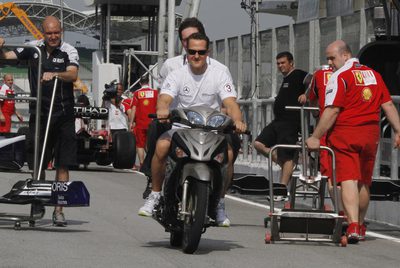 Michael Schumacher se pasea en moto por la calle de garajes del circuito de Sepang.